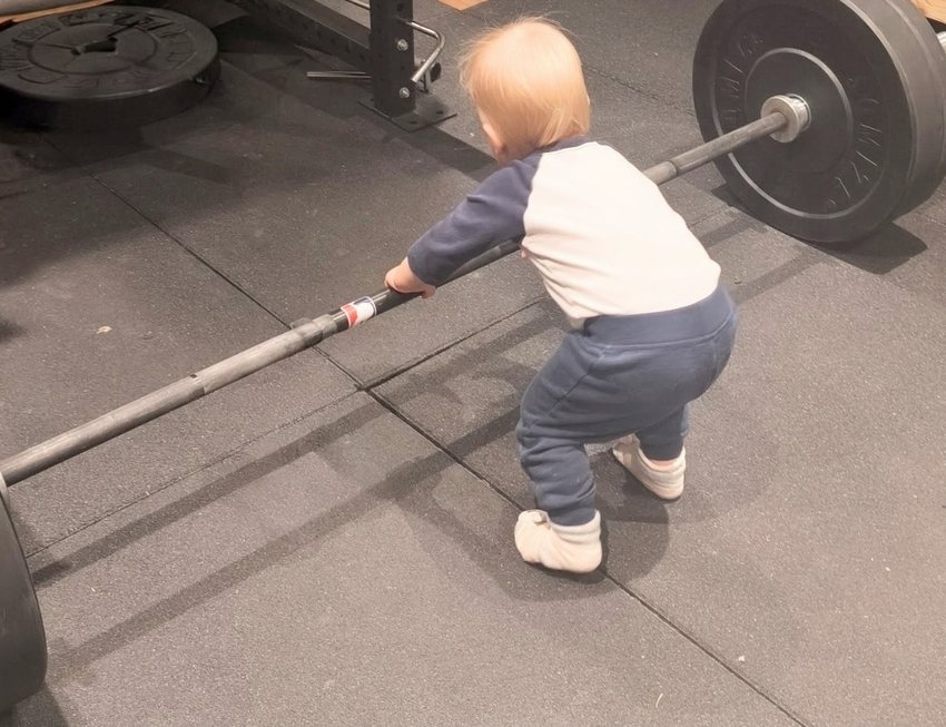 Kind neben einer Langhantel im Fitnessstudio